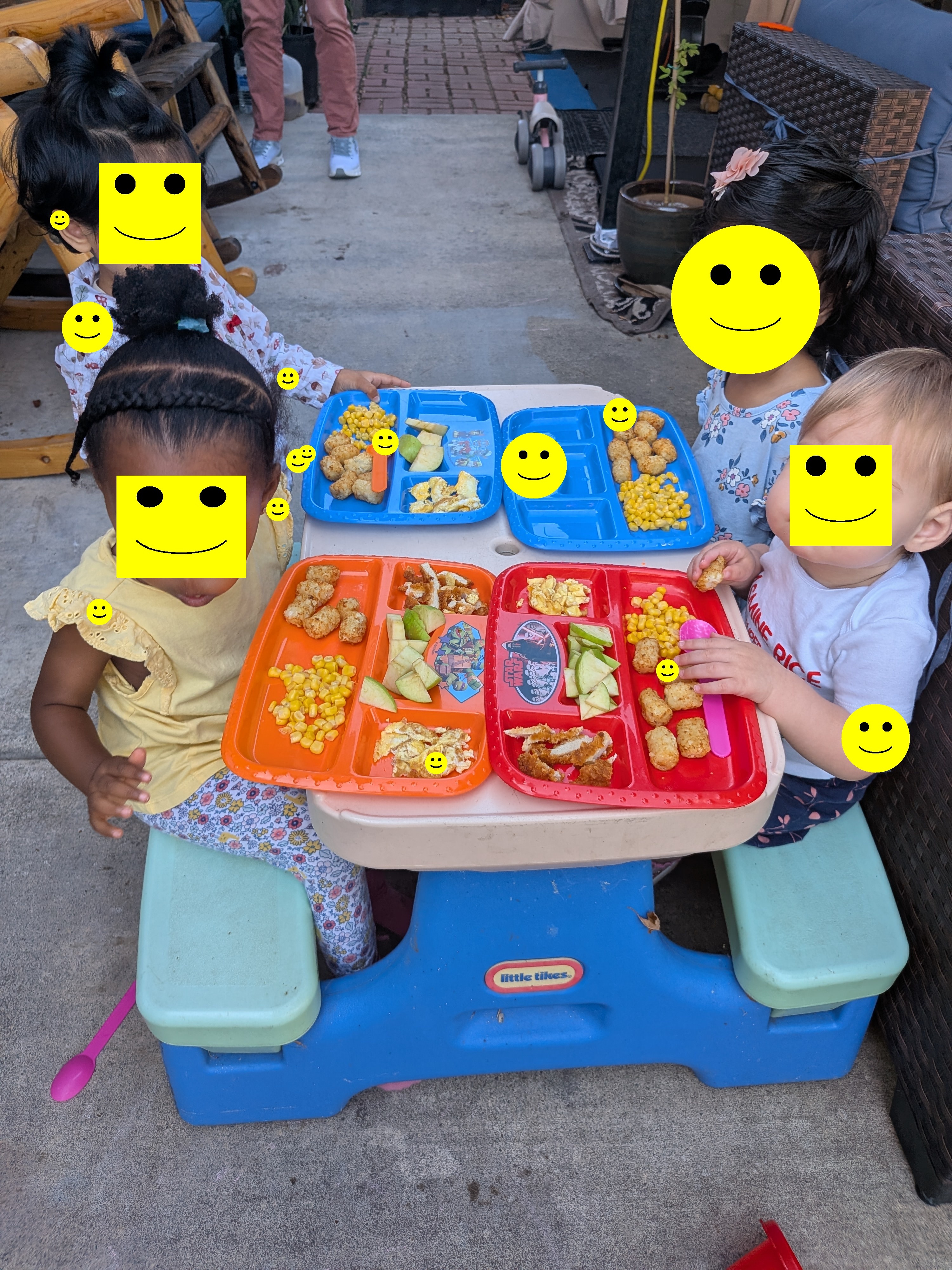Children eating a wholesome home-cooked lunch together at the table outdoors